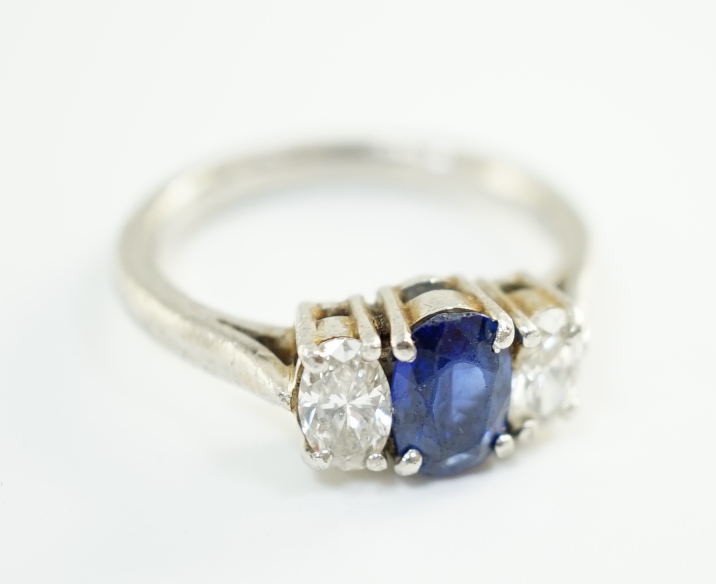 A modern platinum, singe stone oval cut sapphire and two stone oval cut diamond set ring